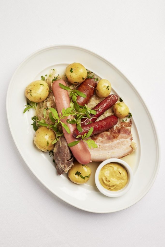 Choucroute Vosgienne med dampet, fermenteret hvidkål, pølser, svinekød, nye kartofler og sennep – en klassisk alsacisk specialitet serveret på Restaurant L’Alsace.