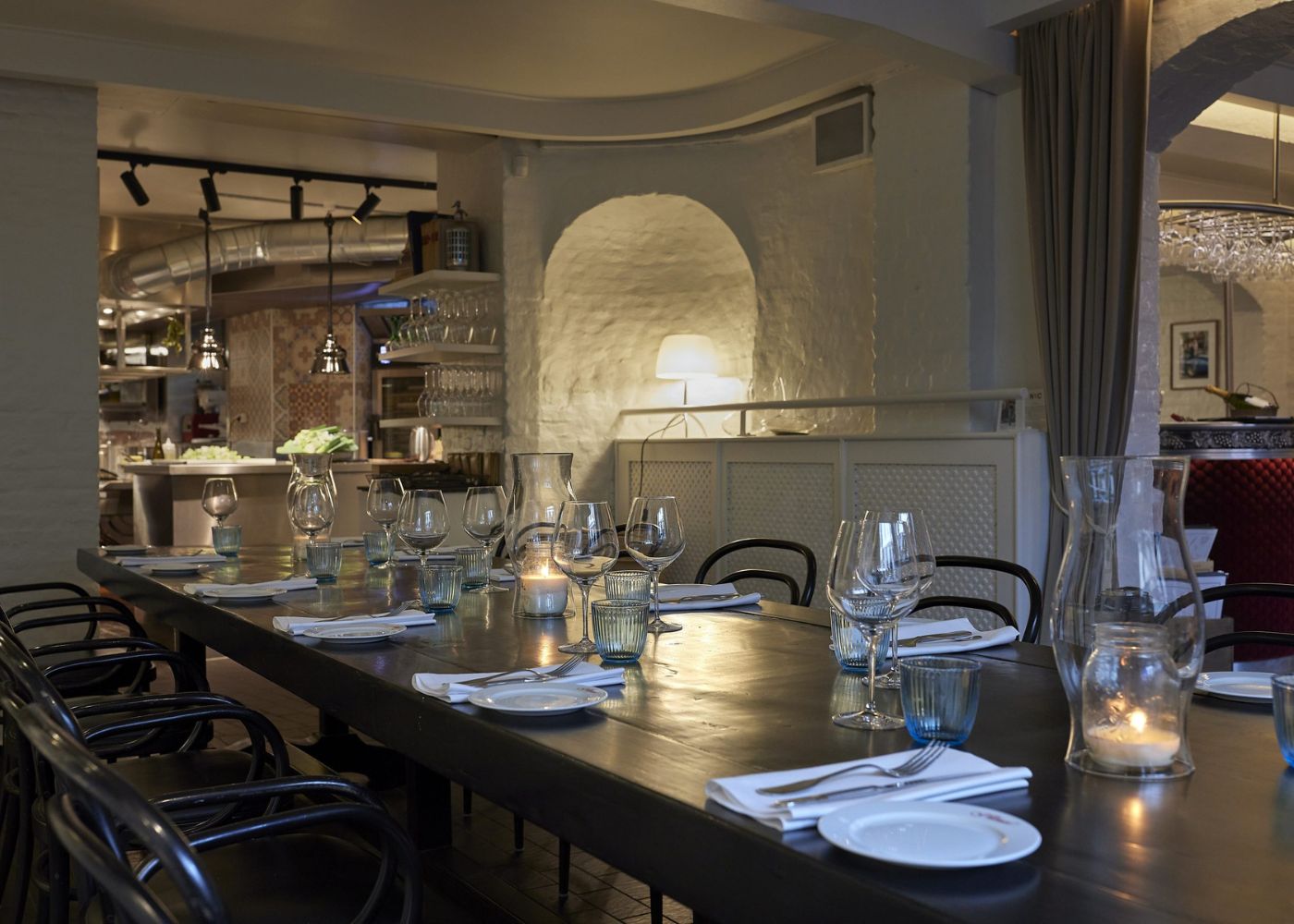 Langbord dækket op til middag i Restaurant L’Alsace i København med glas, service og stearinlys i restaurantens indendørs lokaler.